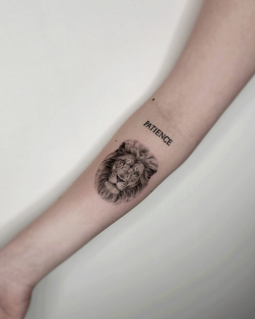 Lion face tattoo with 'patience' word lettering on the forearm: patience pride