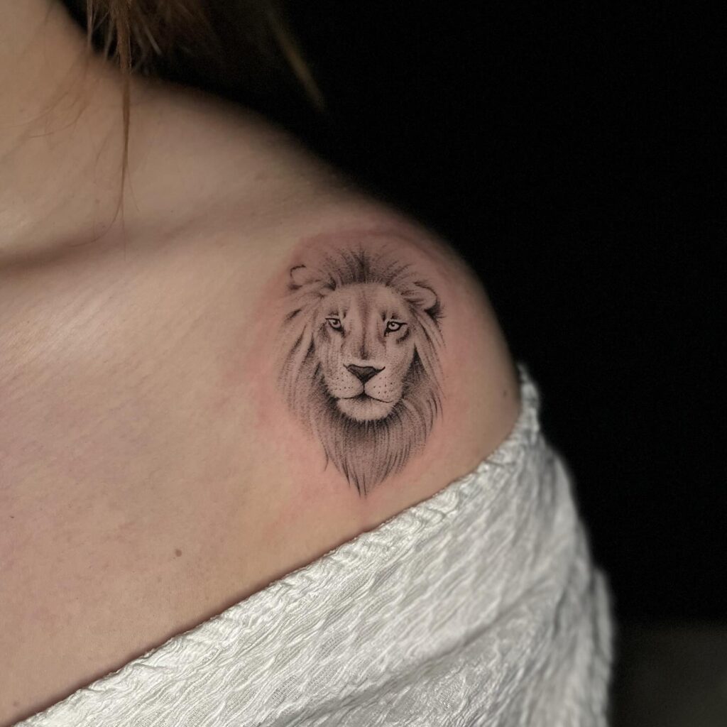 Lion head tattoo on the shoulder, light grey ink shaded, adding an element of grace for women shoulder majesty