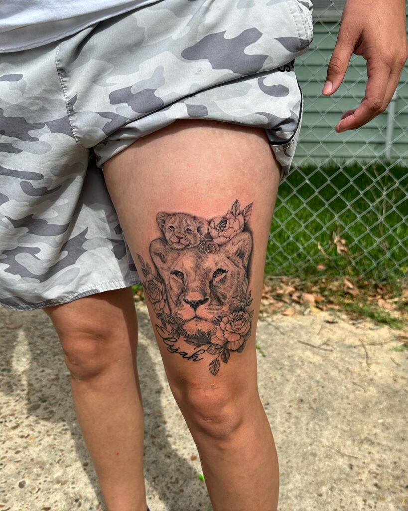 Lioness and cub with floral above the knee tattoo: maternal grace