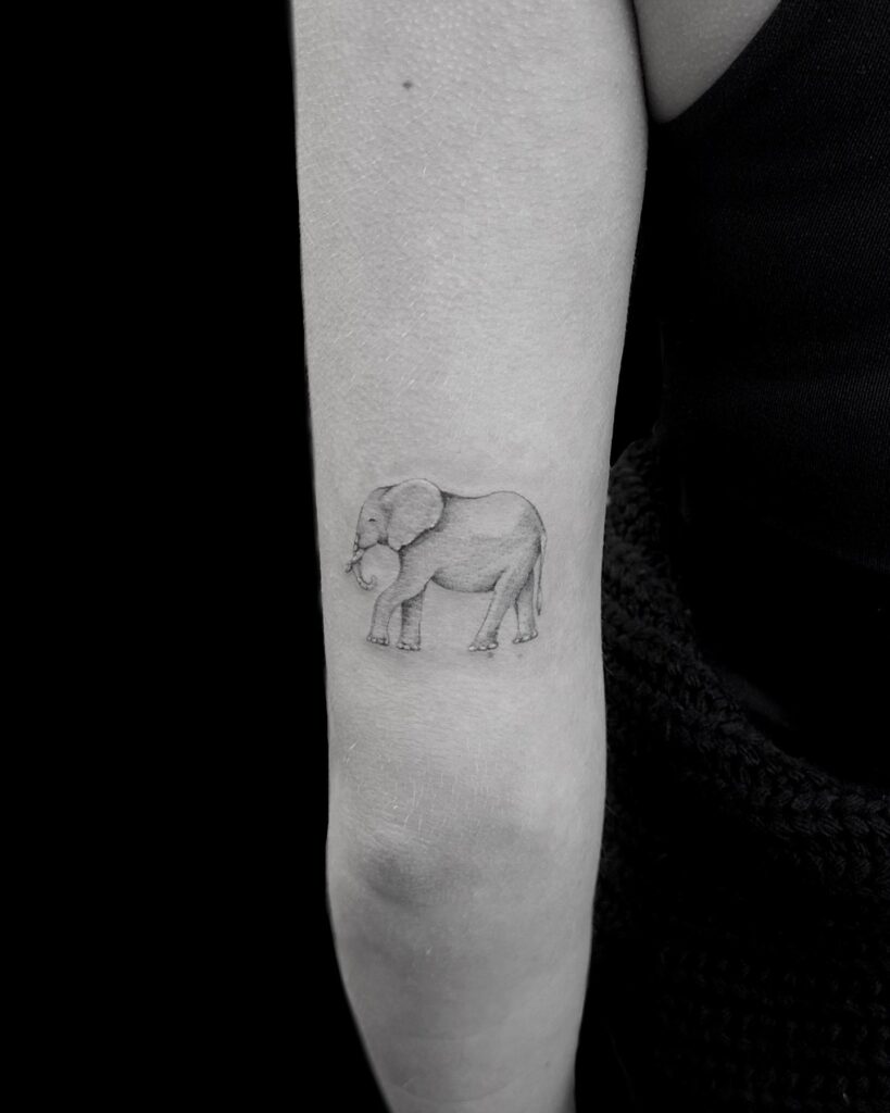 Little elephant side view tattoo: subtle charm above the elbow