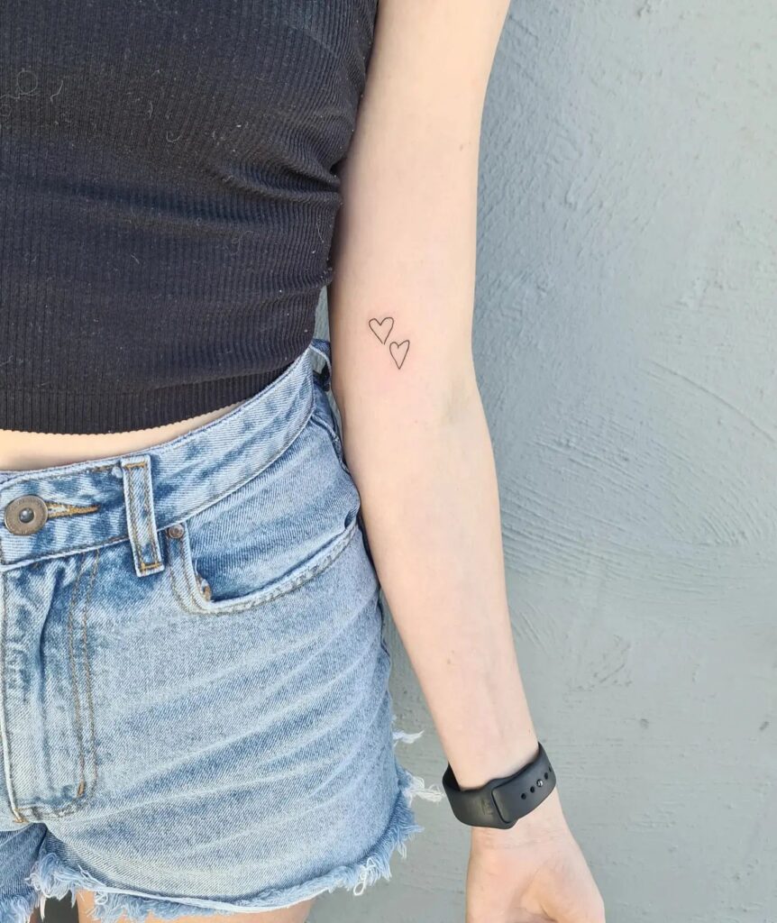 Little two outline love hearts tattoo above the elbow a subtle elegance