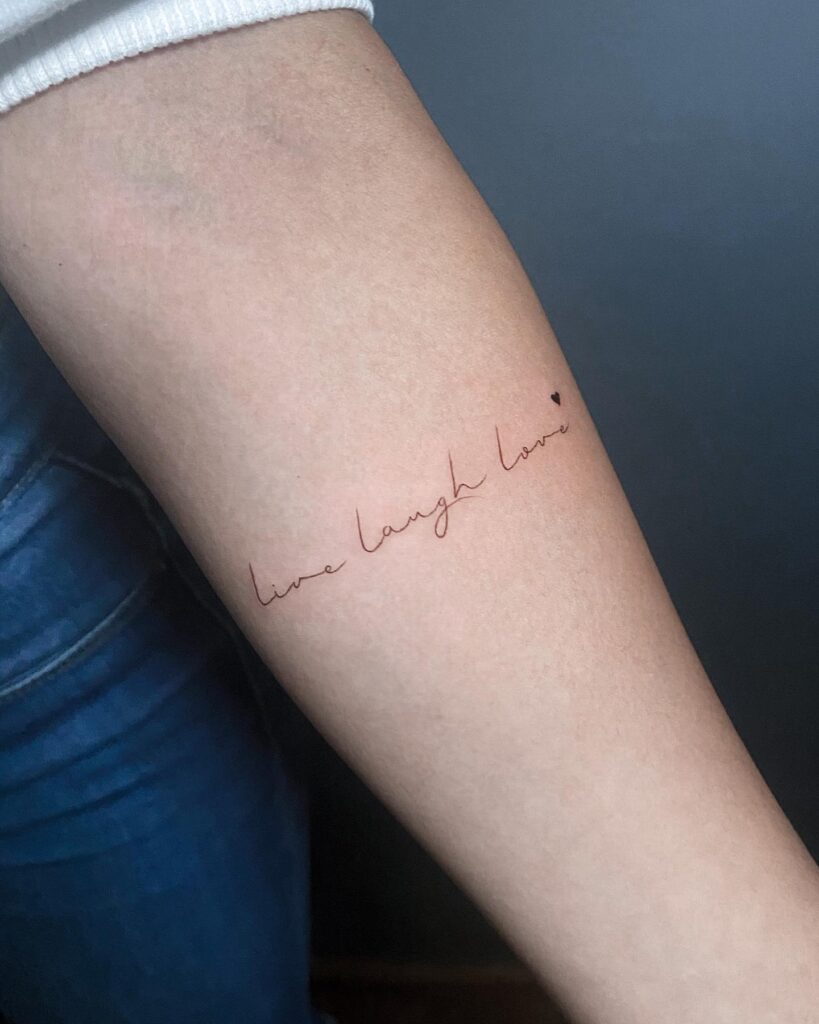 Live laugh love in calligraphy on the inner forearm