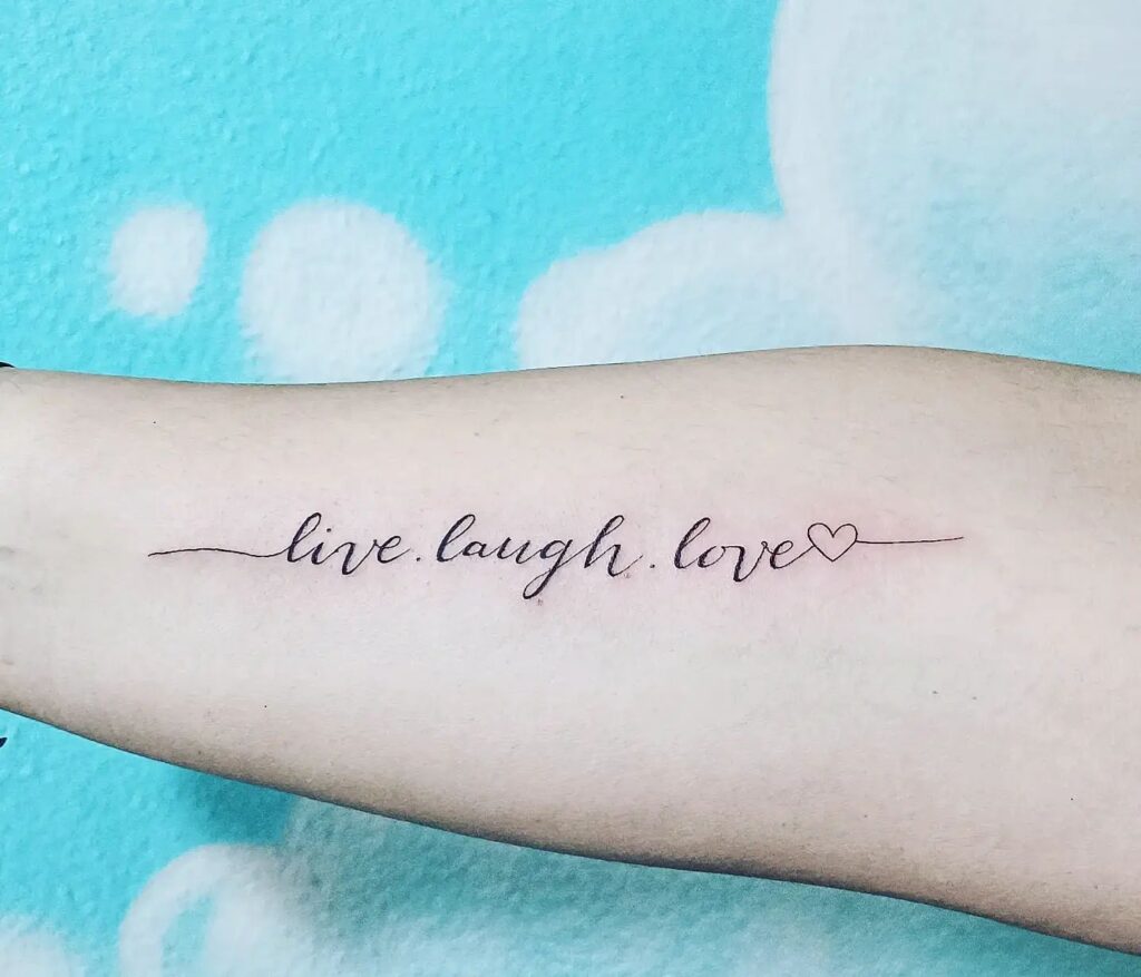 Live laugh love in italic font on the forearm