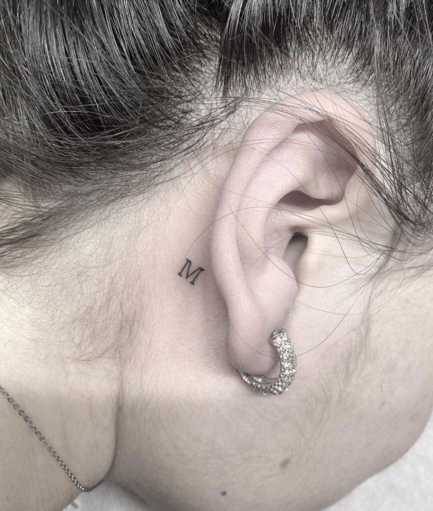 'M' Letter Mini Tattoo Behind the Ear: Whispers of Elegance, a Delicate Accent