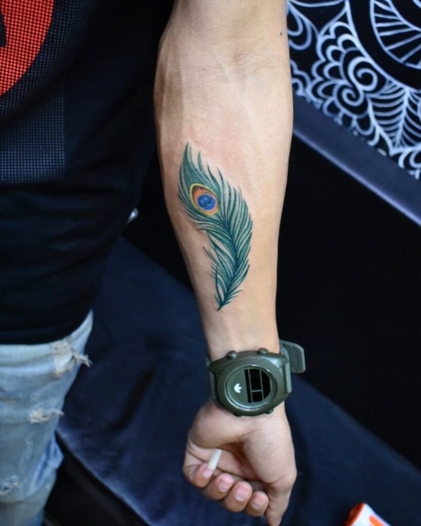 Masculine beauty striking peacock feather inner forearm tattoo for men