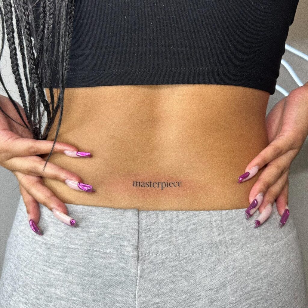 Masterpiece Text Lettering Tattoo on the Lower Back for Women: Feminine Mastery