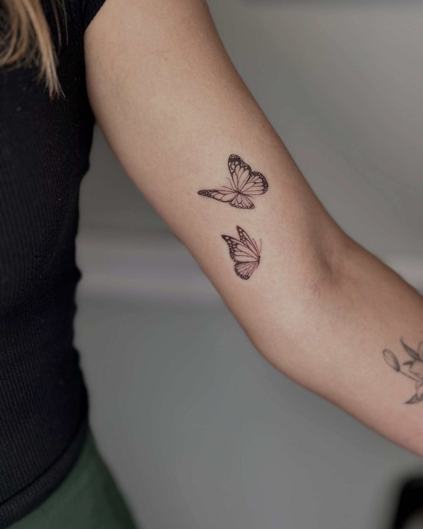 Matching fine-line butterfly tattoos on inner arm symbolism