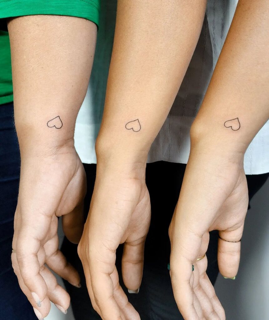 Matching minimal outline heart tattoos on the side of the wrist, symbolizing unity and love for each family member: family ties