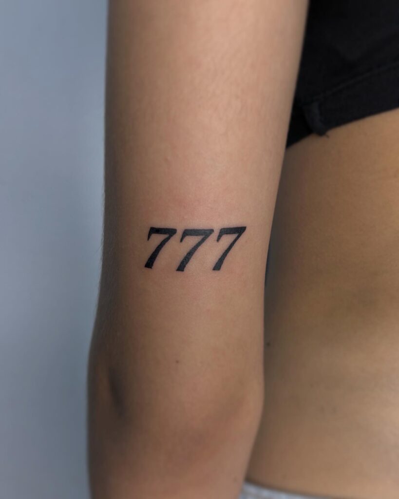 Medium-sized bold 777 number tattoo on the back of the upper arm arm ambiance 