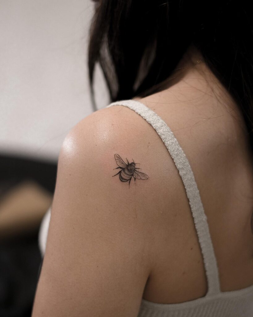 Micro bee tattoo on the back shoulder skipper