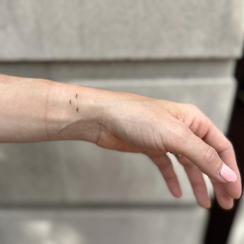 Micro three birds tattoo gracefully adorning the side wrist avian trio