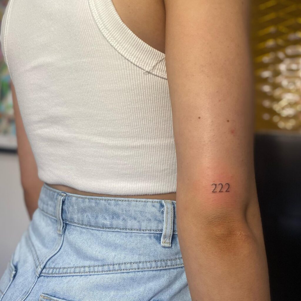 Mini 222 Text Tattoo on the Back of the Above the Elbow for Females, a Subtle Reminder: Mini Message 