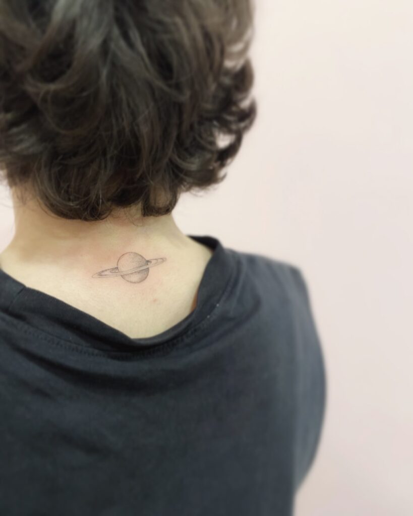 Mini saturn back of the neck tattoo grey shaded celestial beauty