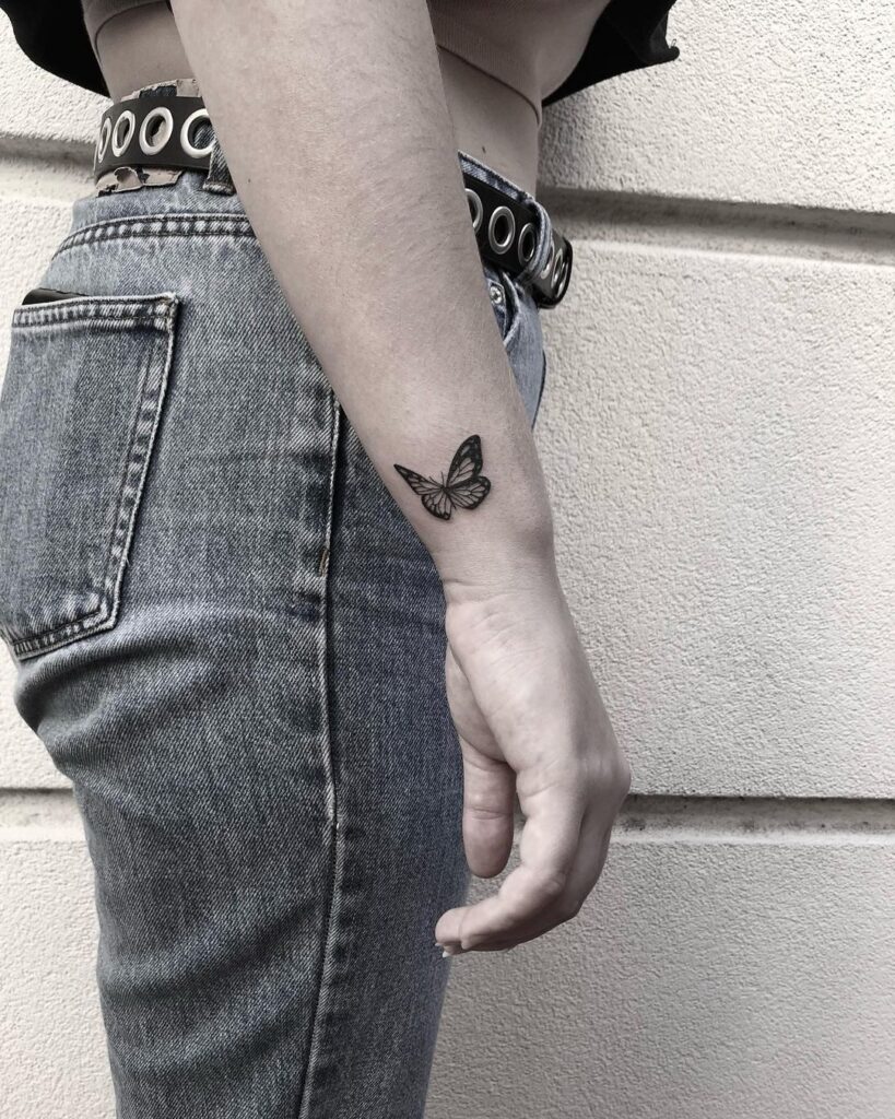 Miniature butterfly outline outer side wrist tattoo