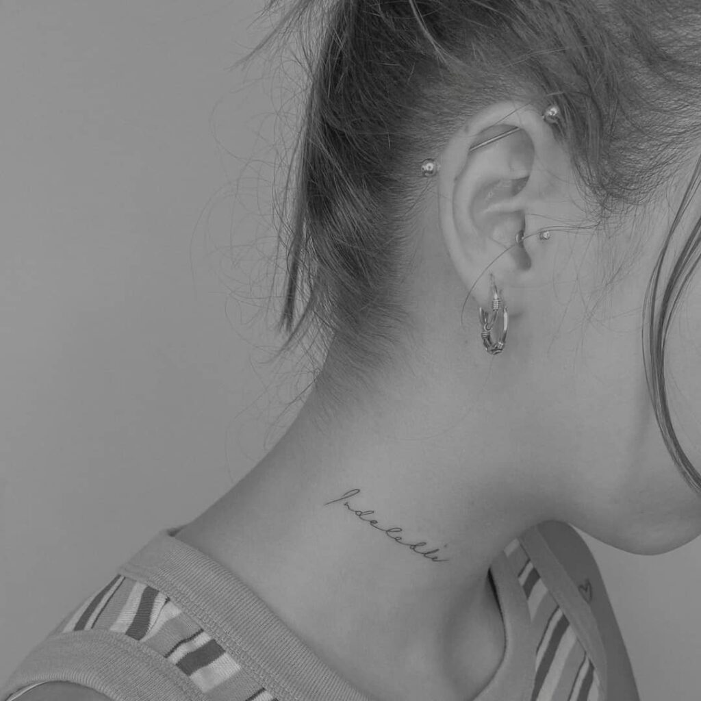 Minimal 'indeleble' word tattoo gracefully placed on the side of the neck indelible mark
