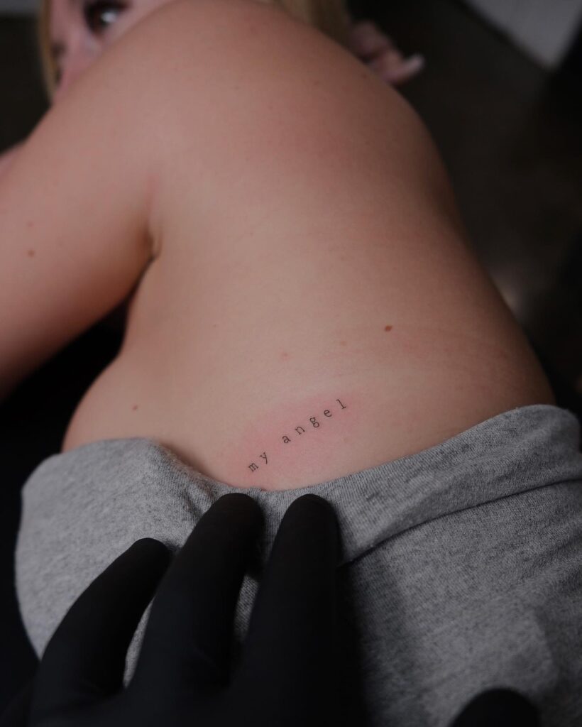 Minimal 'my angel' word lettering tattoo on the side rib elegant and spaced script