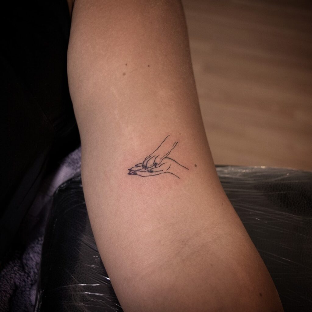 Minimal Tattoo Symbolizing Friendship with Hand and Paw on the Inner Arm: Human-Dog Bond