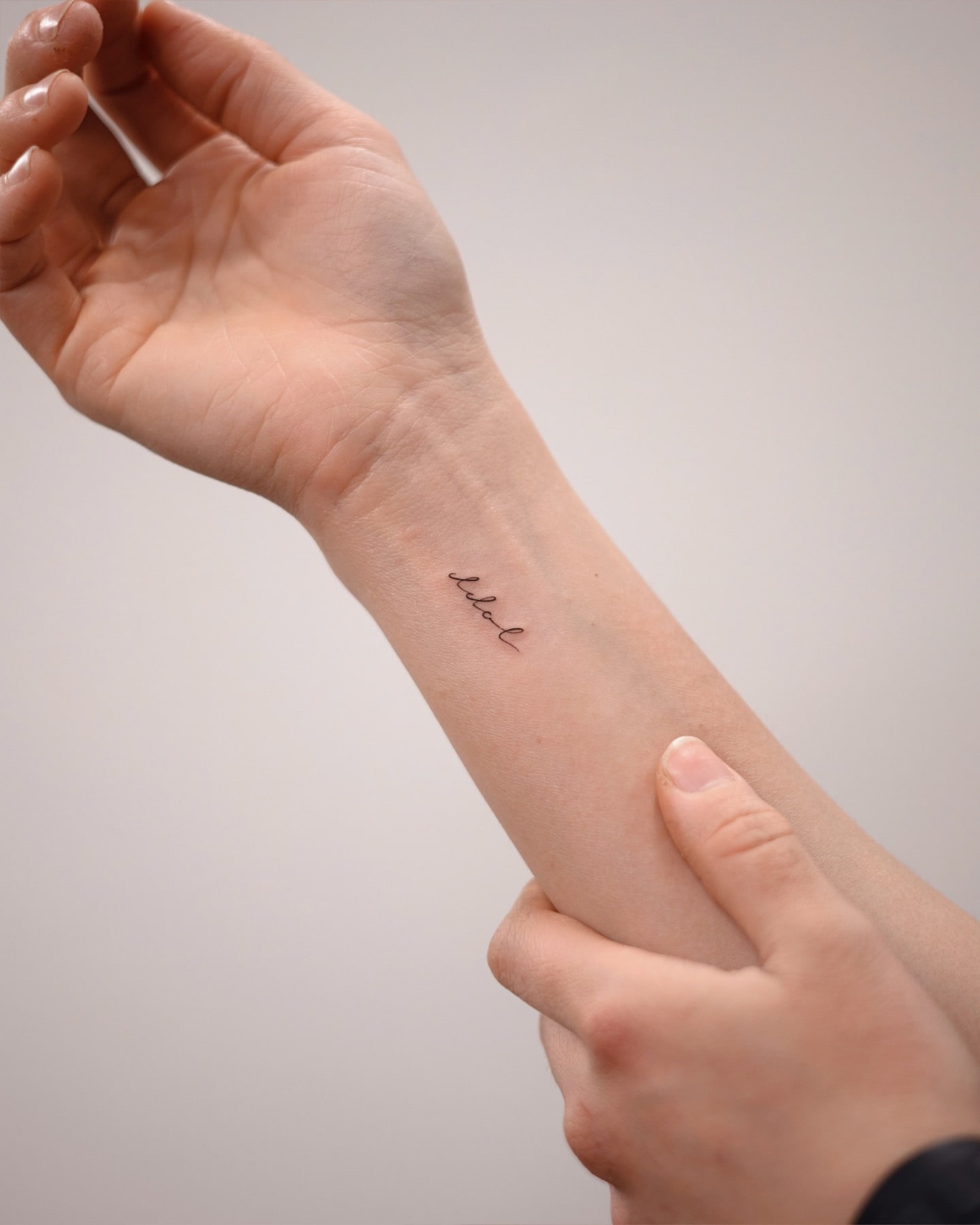 Minimalist cursive script tattoo on wrist subtle meaningful statement