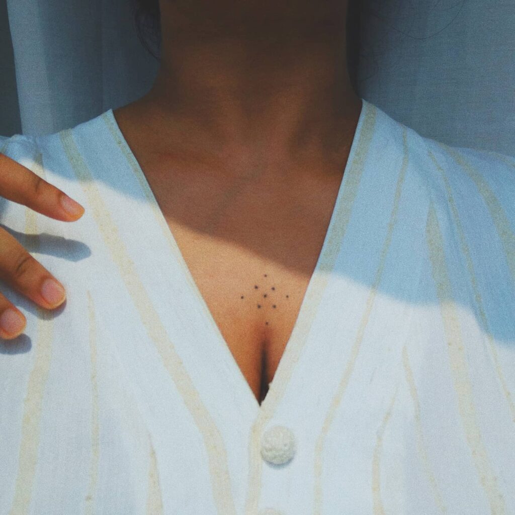 Minimalist dotwork sternum tattoo symbolizing harmony and balance