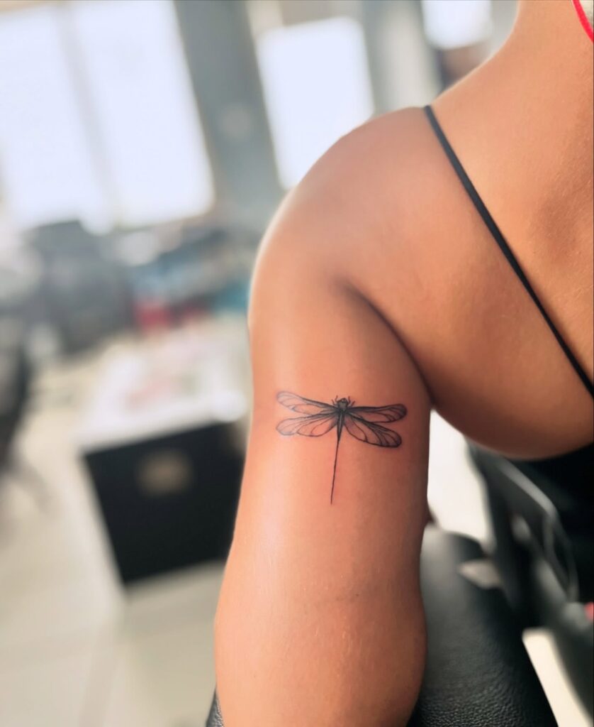 Minimalist Dragonfly Tattoo on Upper Arm Symbolizing Change and Adaptability