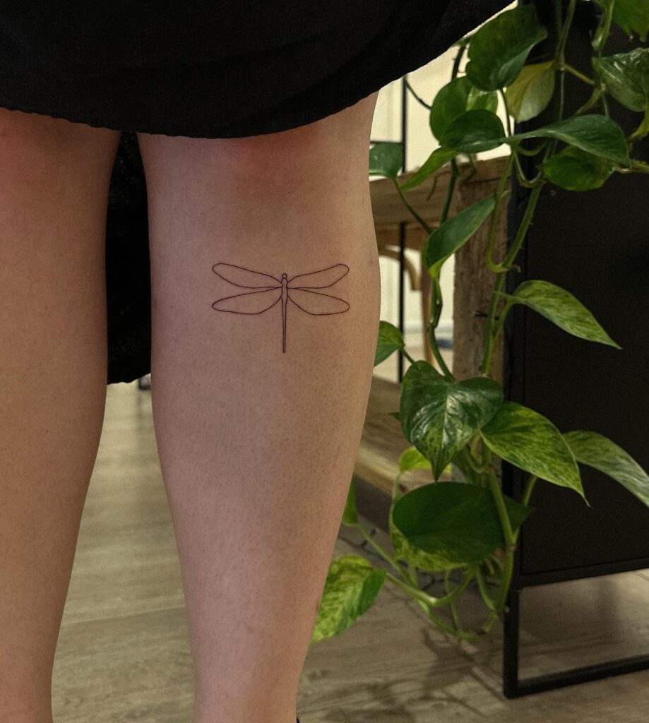 Minimalist Fine-Line Dragonfly Tattoo Below the Knee for Elegance and Transformation