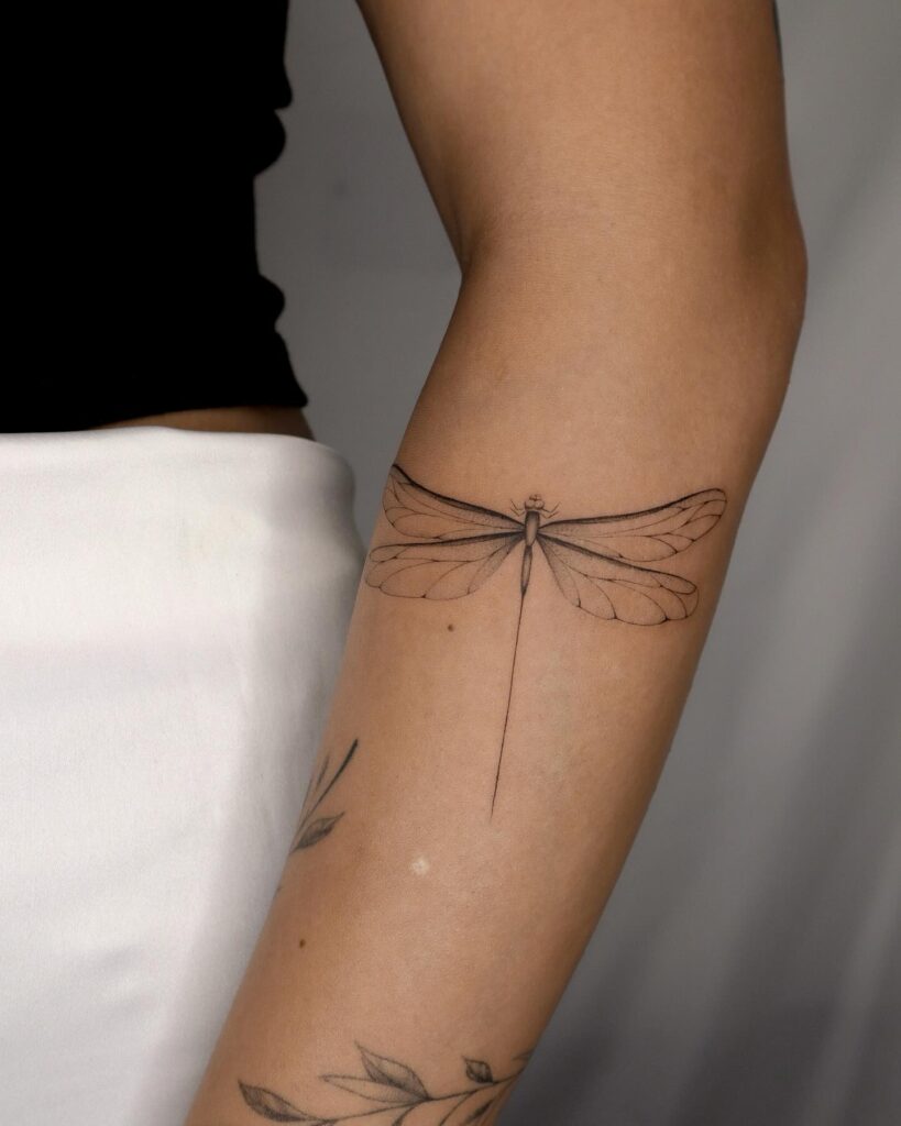 Minimalist Fine-Line Dragonfly Tattoo Blending with Botanical Designs