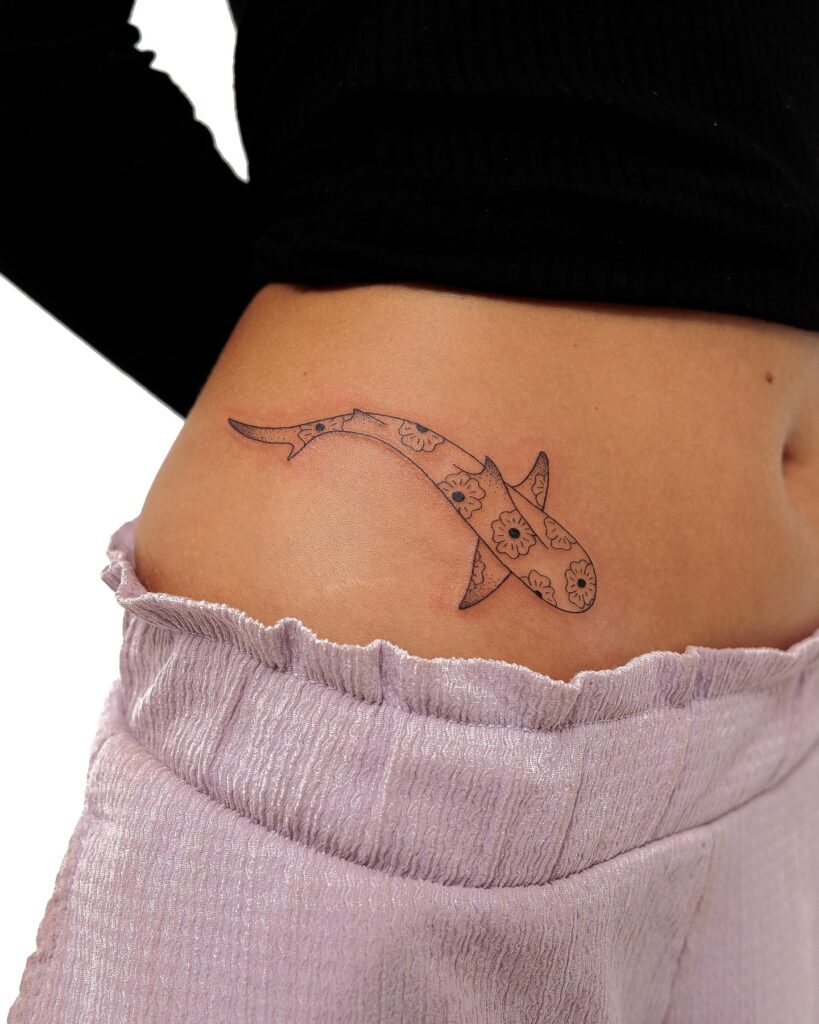 Minimalist floral shark tattoo on the hip combining soft botanical elements with marine symbolism