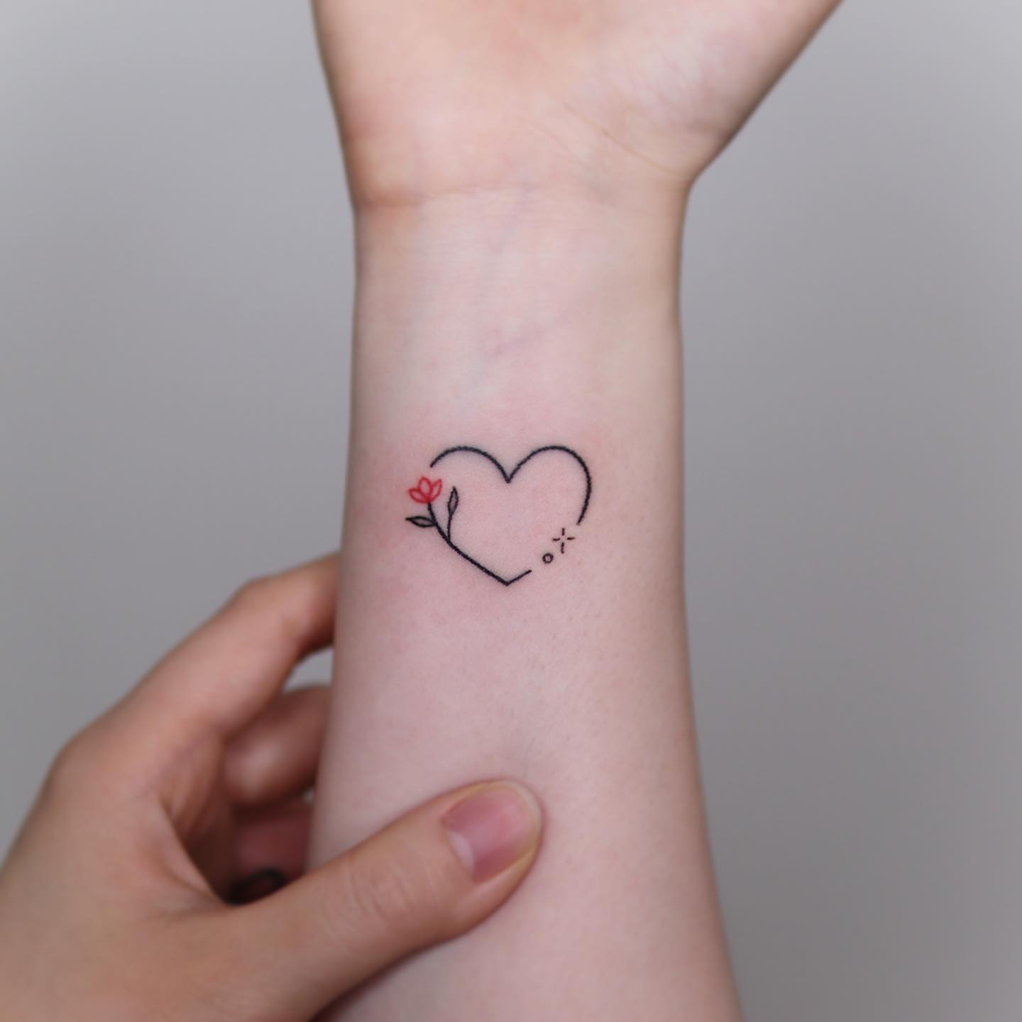 Minimalist heart tattoo with floral accent love self care