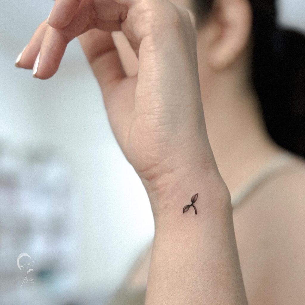 Minimalistic tiny leaves wrist tattoo: two leaves, simple and elegant