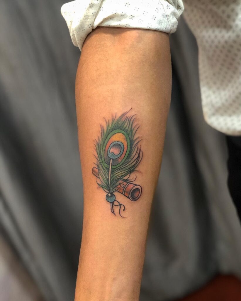 Musical harmony peacock feather tattoo with flute on the forearm for men