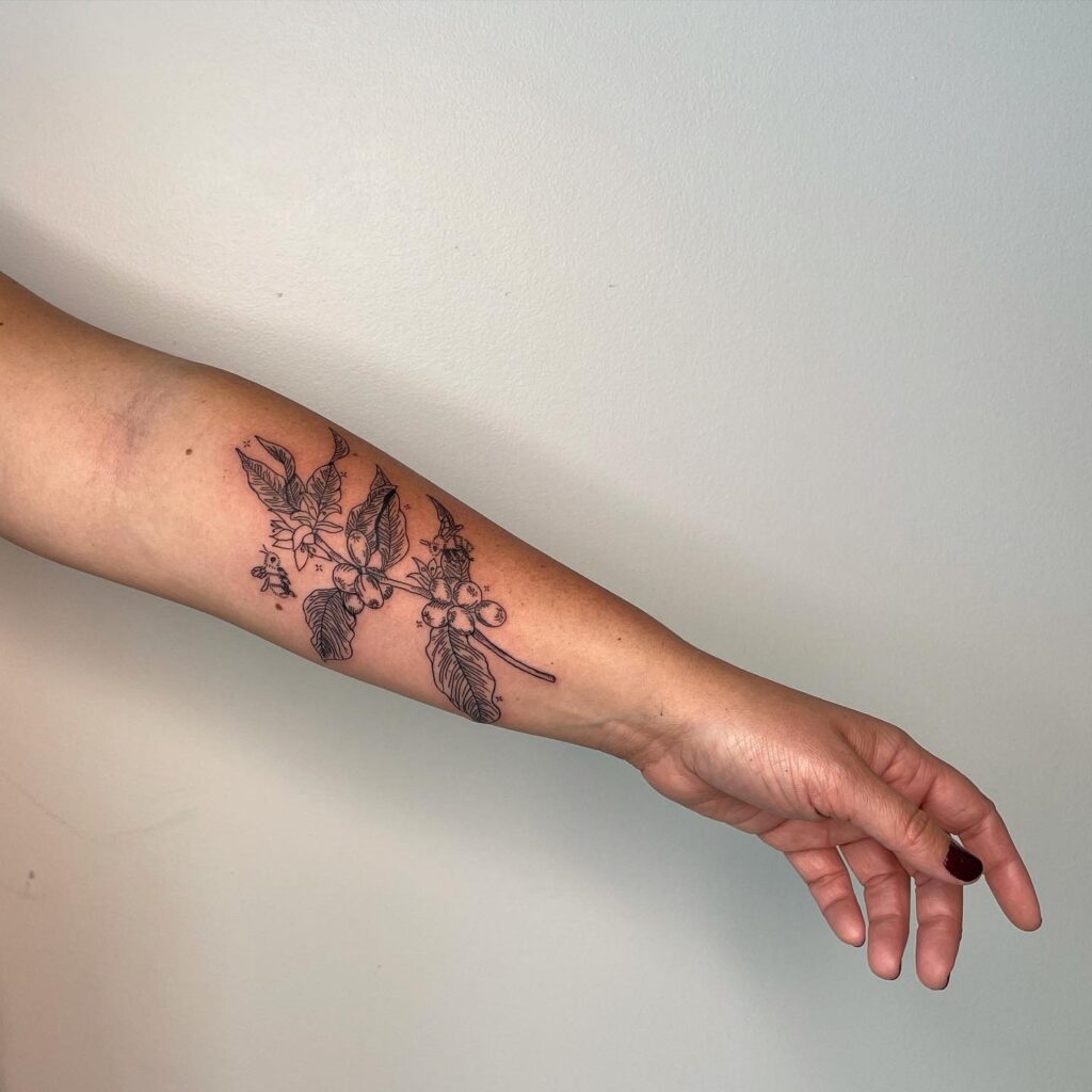 Nature's blend coffee plant and bee tattoo on forearm