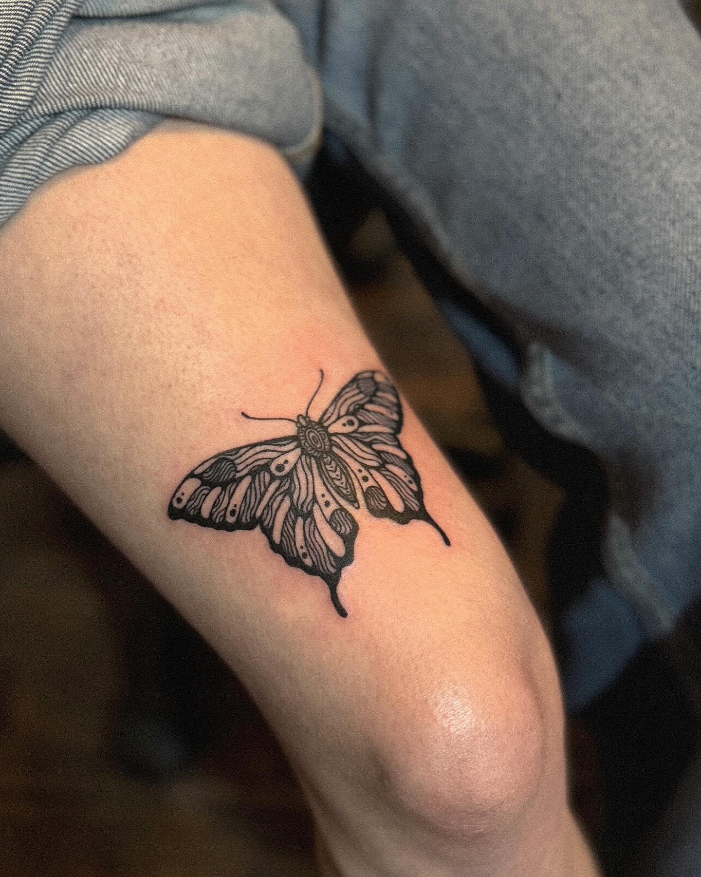 Neo-traditional butterfly tattoo with bold outlines and ornamental patterns
