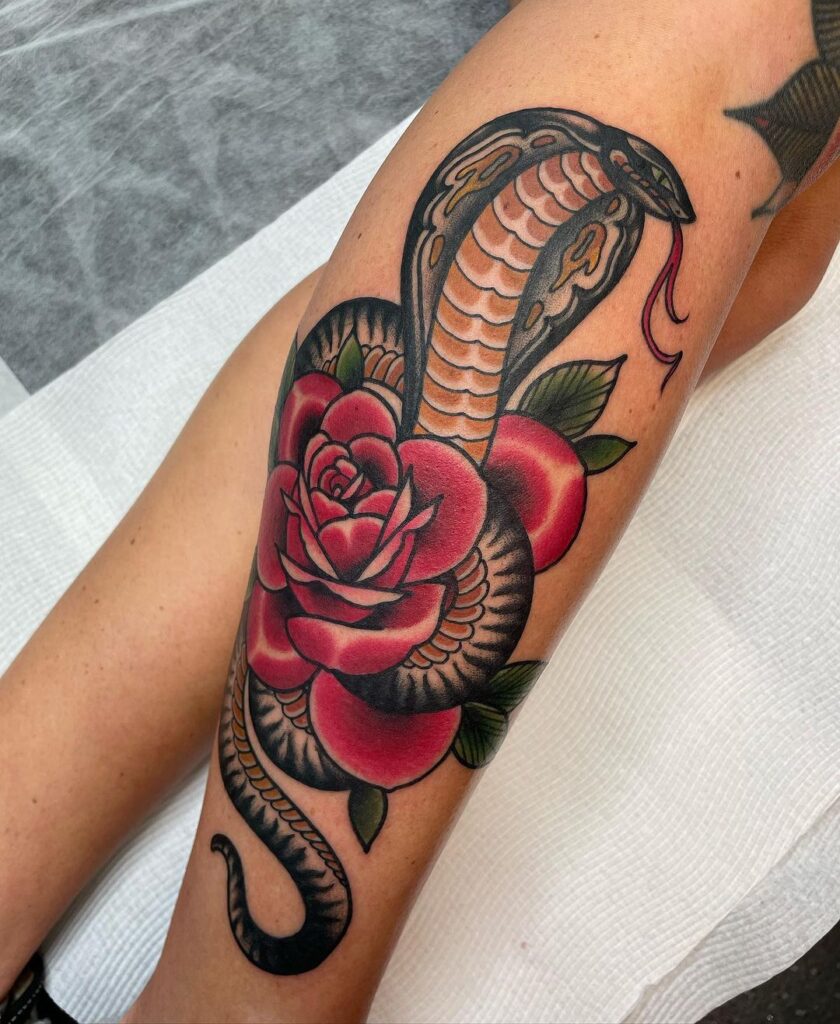 Neotraditional cobra tattoo colorful serpent wrapping around a rose on calf