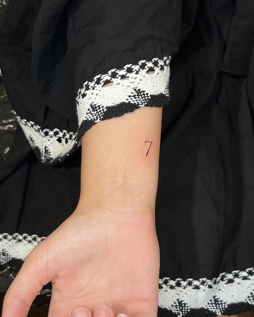 Number 7 tattoo on the inner wrist for females, a subtle wrist adornment: Lucky seven accent