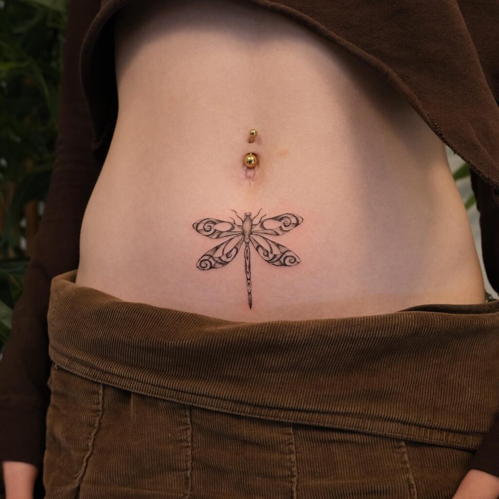 Ornamental Dragonfly Tattoo Below the Navel with Swirls and Fine Linework