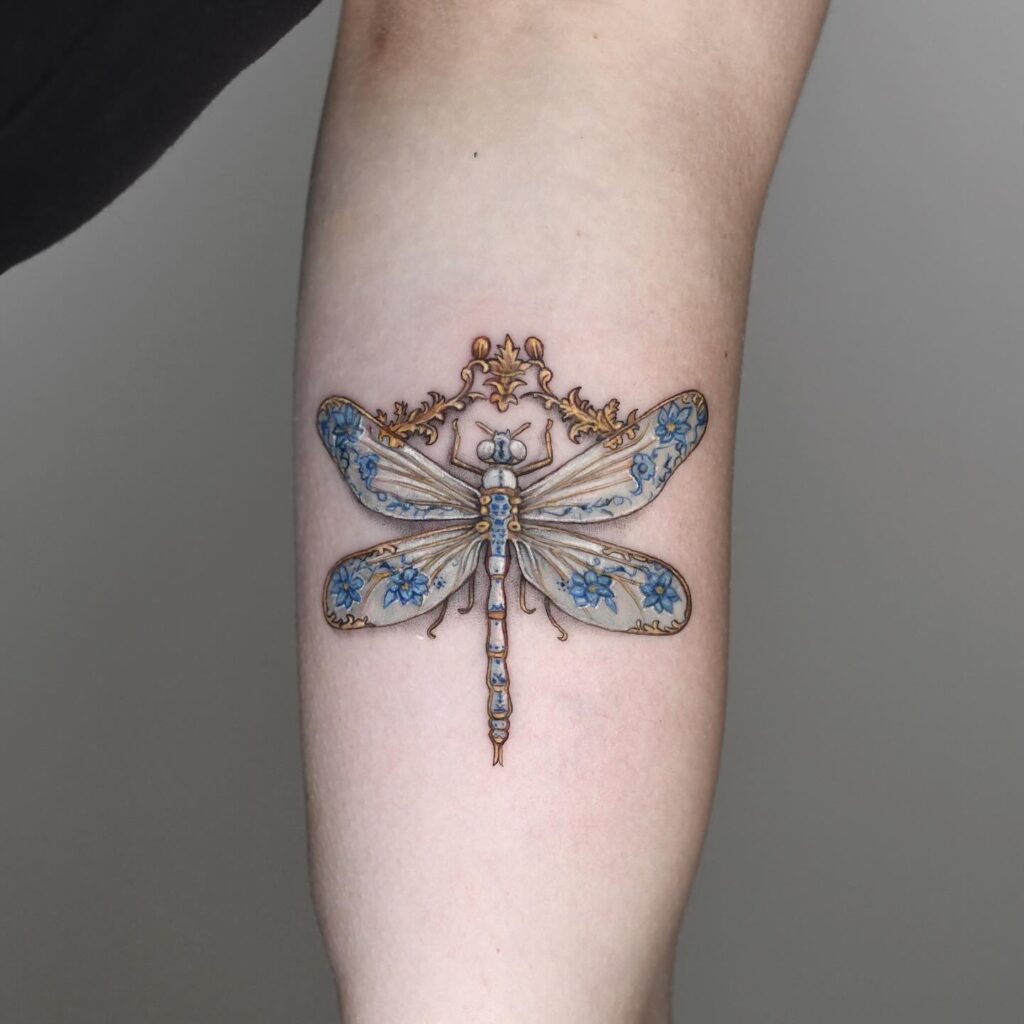 Ornamental Dragonfly Tattoo with Blue Flowers and Gold Embellishments