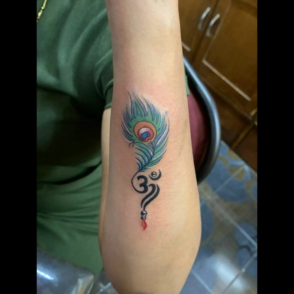 Outer Forearm Peacock Feather Tattoo with Om Symbol Spiritual Expression