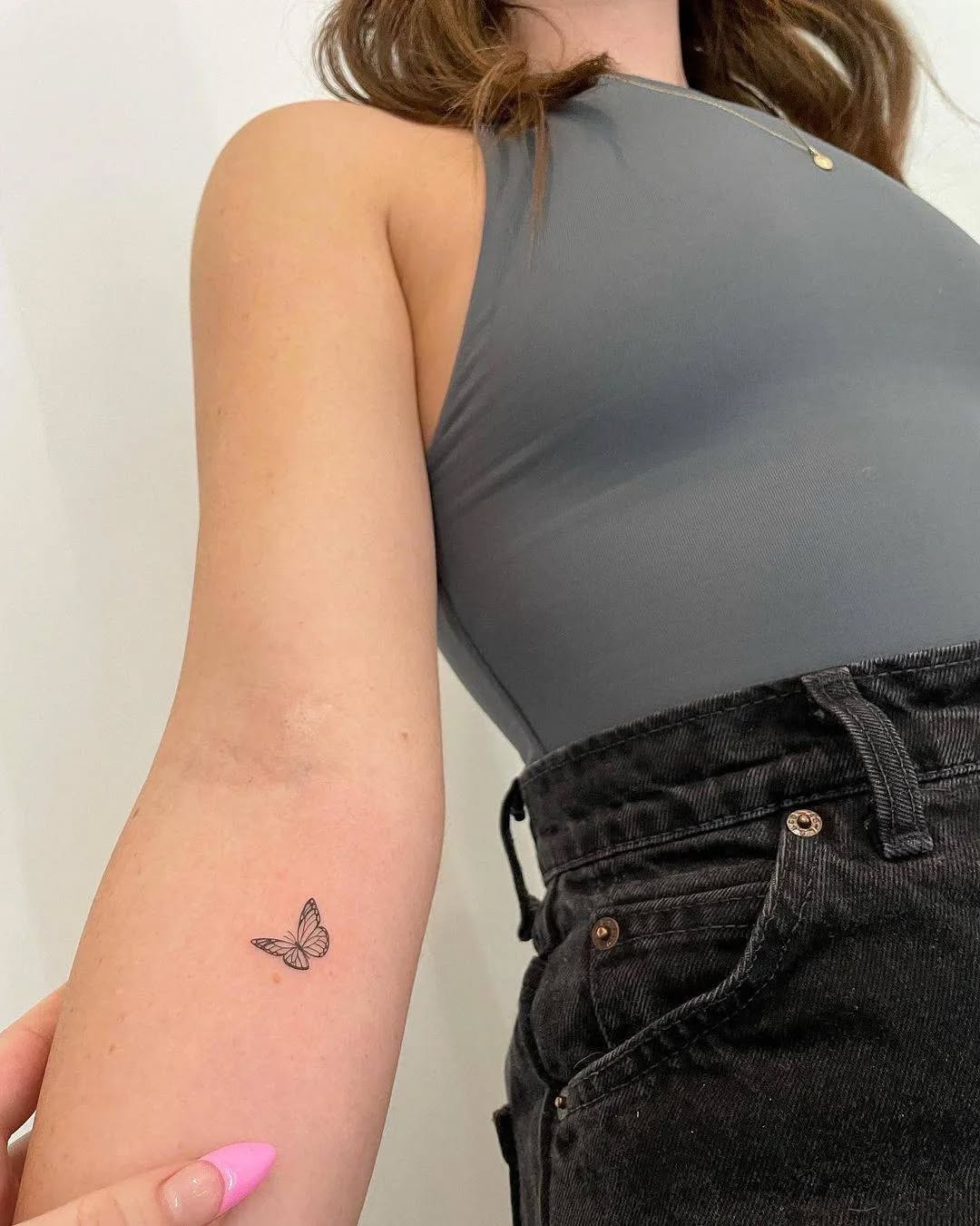 Outer arm butterfly tattoo above elbow with minimalist linework