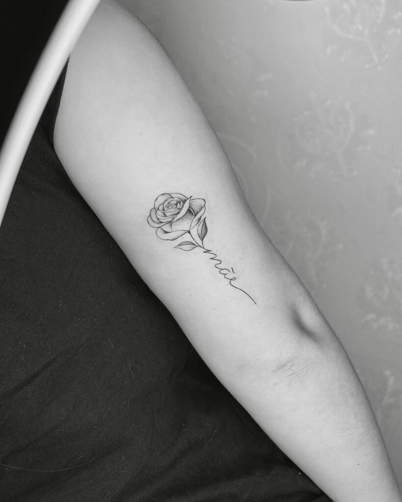 Outer arm rose with the script lettering 'mãe,' a grey shaded tribute to motherhood: maternal bloom