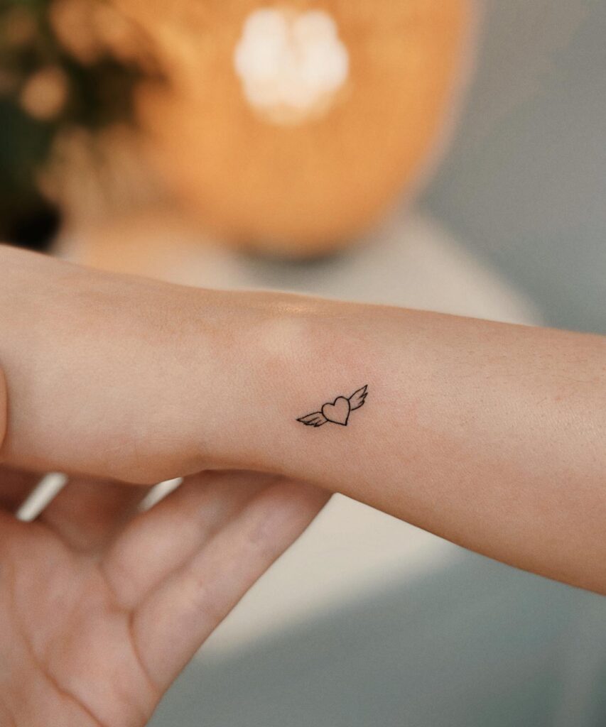 Outline Heart with Wings Tattoo on the Side of the Wrist: Winged Affection