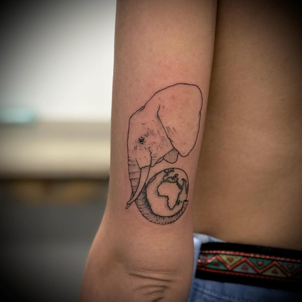 Outline side view head with globe on the back of the elbow: globetrotting elephant
