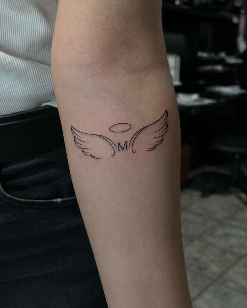 Personal & stylish wings tattoo below elbow with the letter m