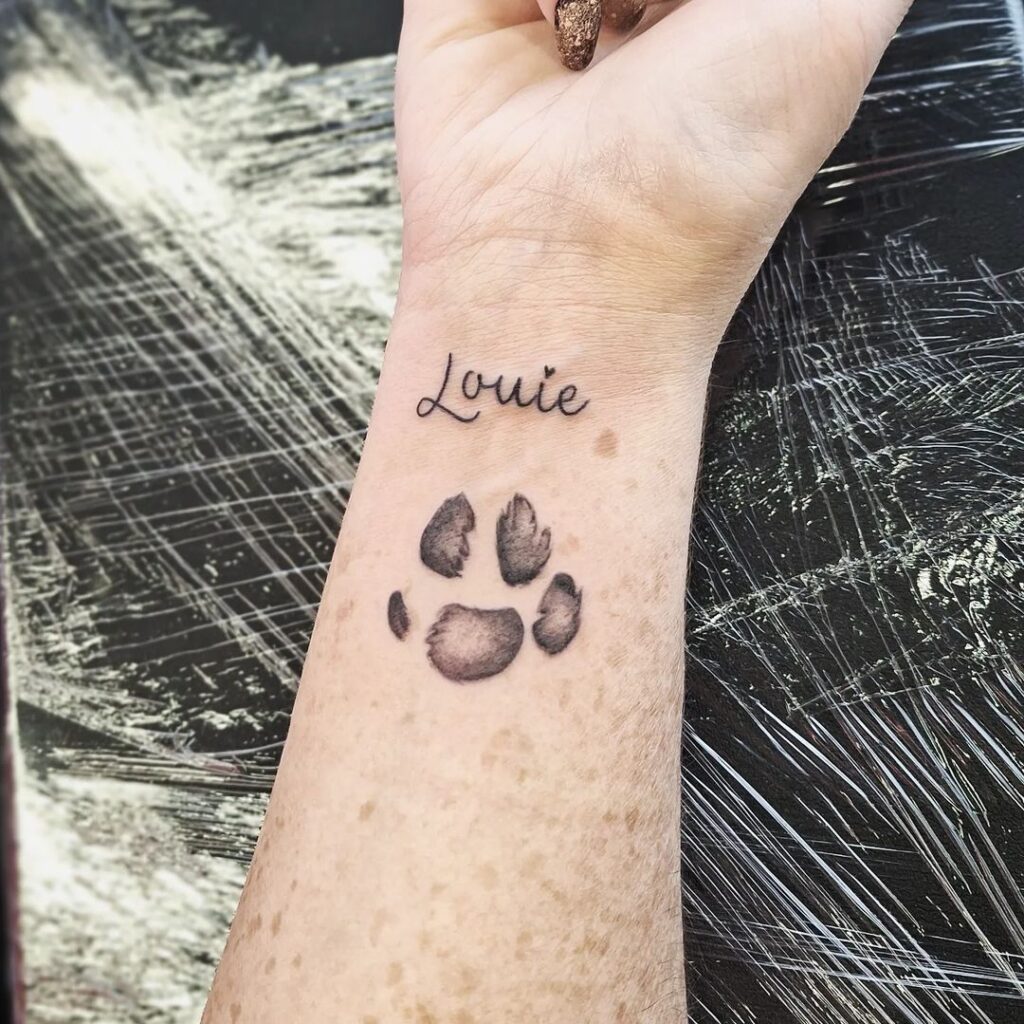 Personalized touch dog paw with 'Lauie' text tattoo on the wrist