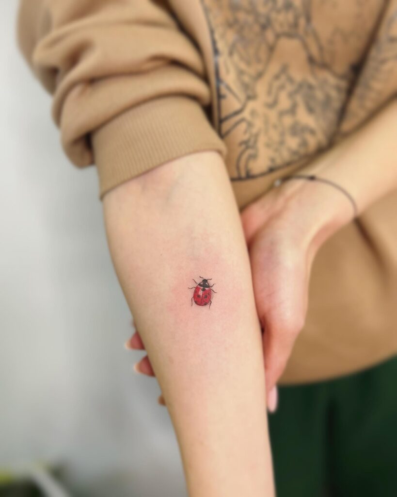 Playful and chic ink girl forearm ladybug tattoo design