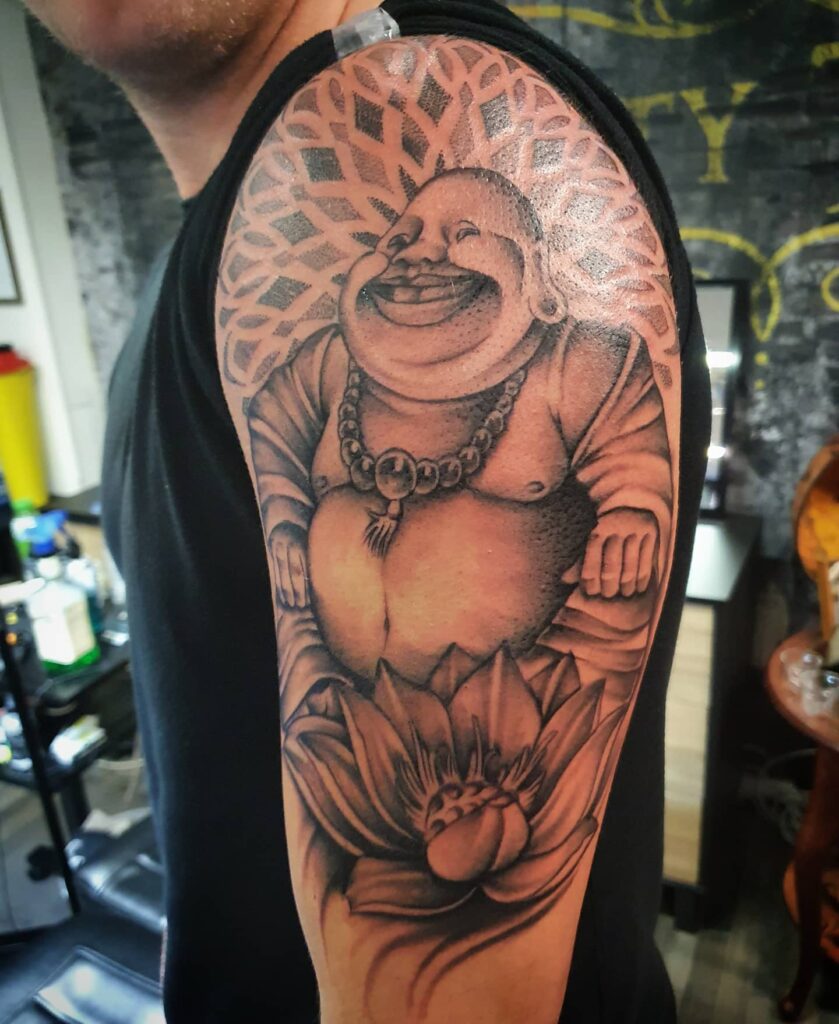Realistic Laughing Buddha Upper Arm Tattoo with Lotus Growth and Enlightenment 