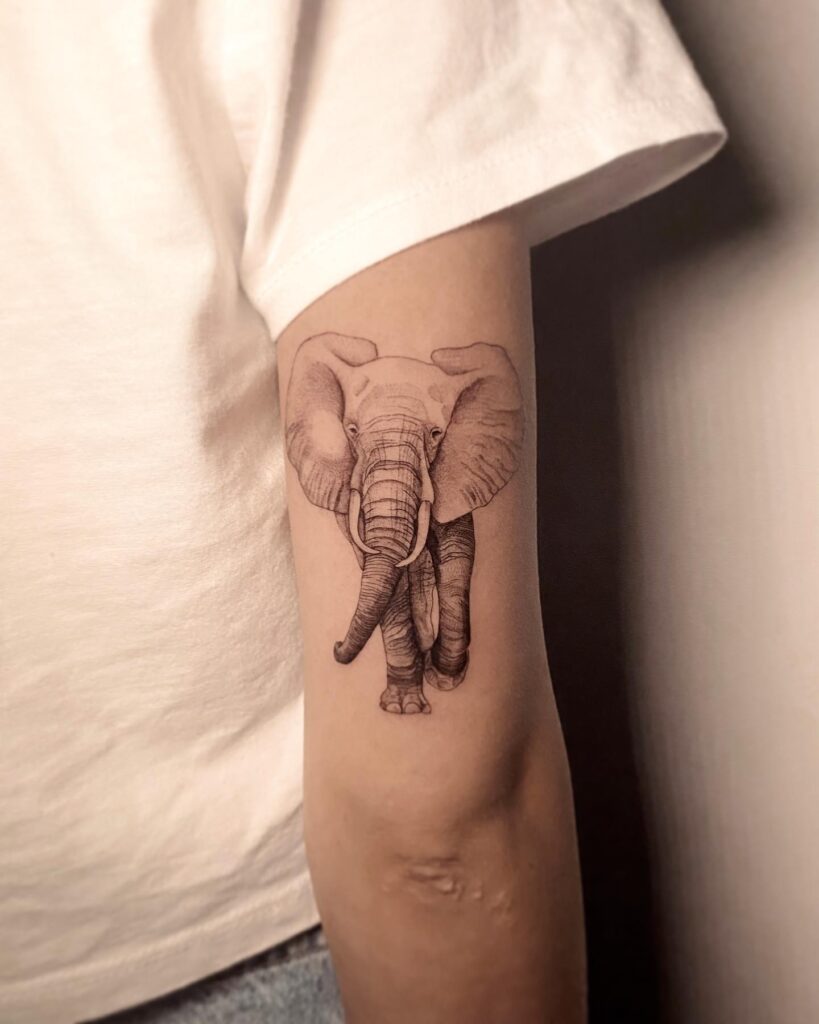Realistic black and gray elephant tattoo on back of the arm, capturing the elephant's front view with stunning detail lifelike grace