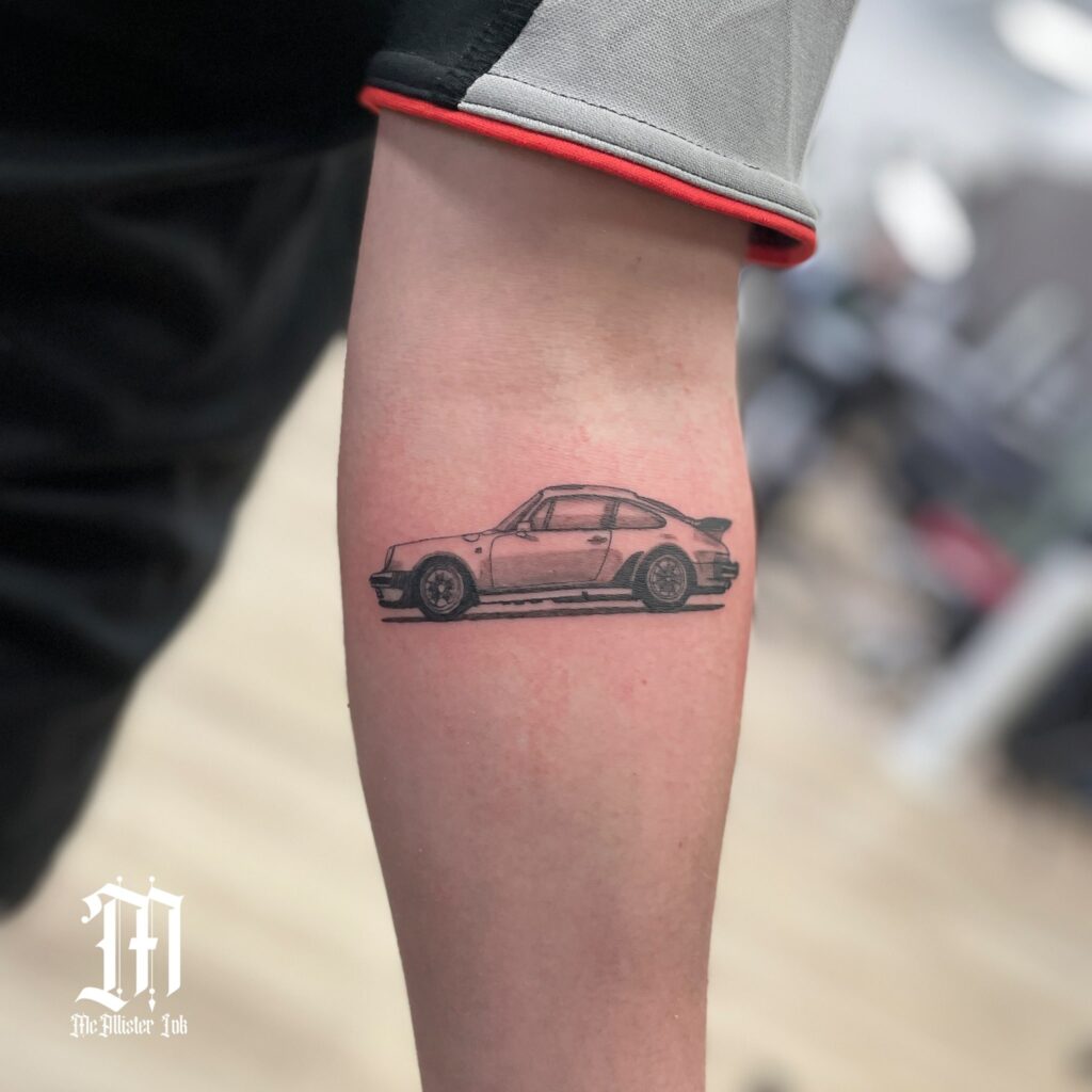 Realistic Black and Grey Porsche 911 Tattoo with Bold Shading on Forearm – Car Tattoo Ideas