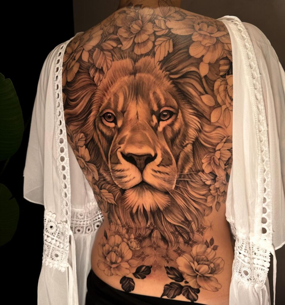 Realistic eye catching fully covered back tattoo for females, featuring a king lion surrounded by flowers, meticulously detailed floral majesty