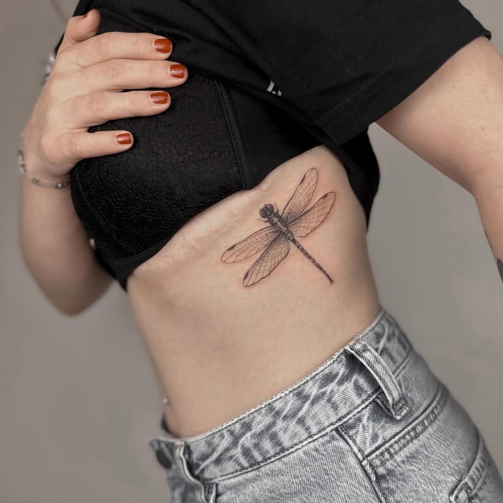 Realistic Fine-Line Dragonfly Tattoo with Ribcage Placement