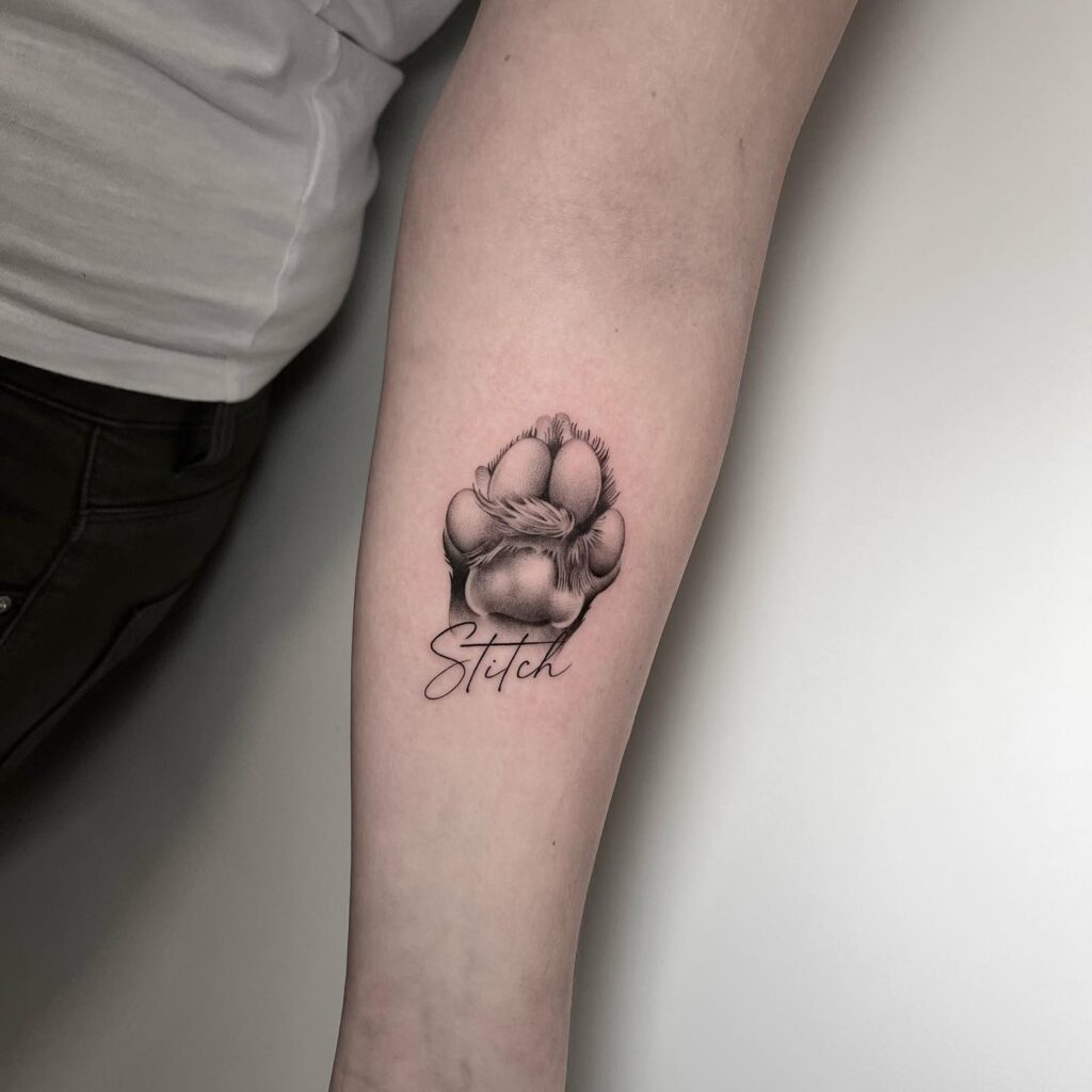 Realistic Paw Tattoo on Inner Forearm with 'Stitch' Lettering: Forever Stitched